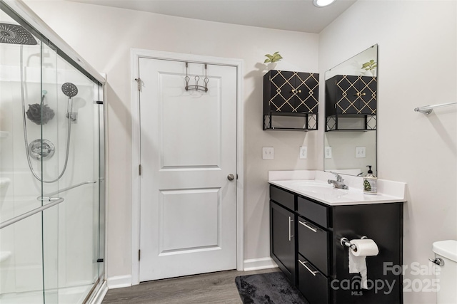 bathroom featuring toilet, a stall shower, wood finished floors, and vanity