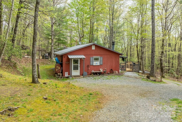 view of front of home with a view of trees and gravel driveway