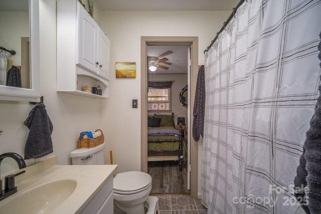 ensuite bathroom with toilet, connected bathroom, ceiling fan, vanity, and tile patterned floors