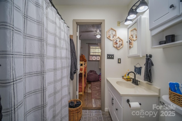 bathroom with toilet, curtained shower, a ceiling fan, and vanity