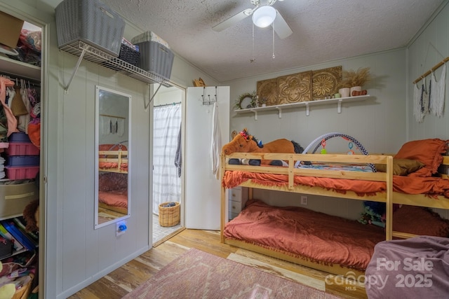 bedroom featuring a textured ceiling, ceiling fan, ornamental molding, and wood finished floors