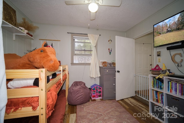 bedroom with ceiling fan, a textured ceiling, and wood finished floors