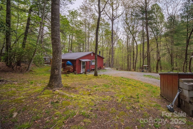 view of yard with gravel driveway and a view of trees