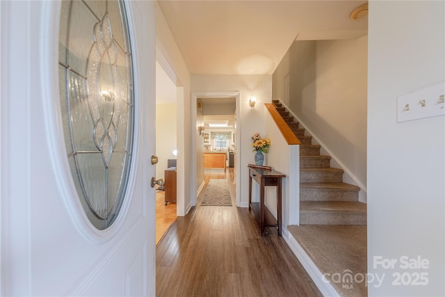 foyer entrance featuring stairs, wood finished floors, and baseboards