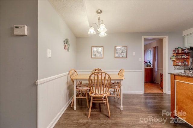 dining space with an inviting chandelier, wood finished floors, and wainscoting