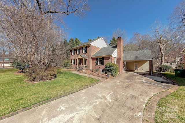 colonial home with brick siding, a chimney, concrete driveway, and a front lawn