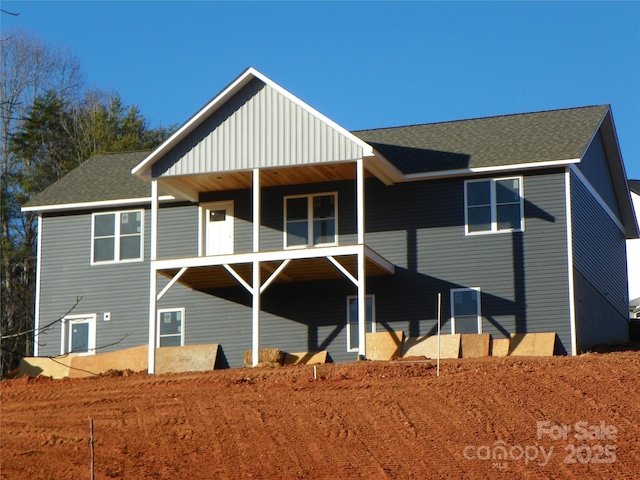 back of house featuring roof with shingles and a balcony