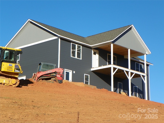 back of property featuring a balcony and a shingled roof