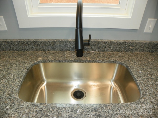 room details featuring dark stone counters and a sink