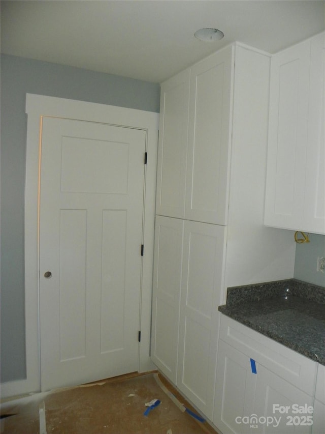 interior space featuring white cabinetry and dark stone countertops