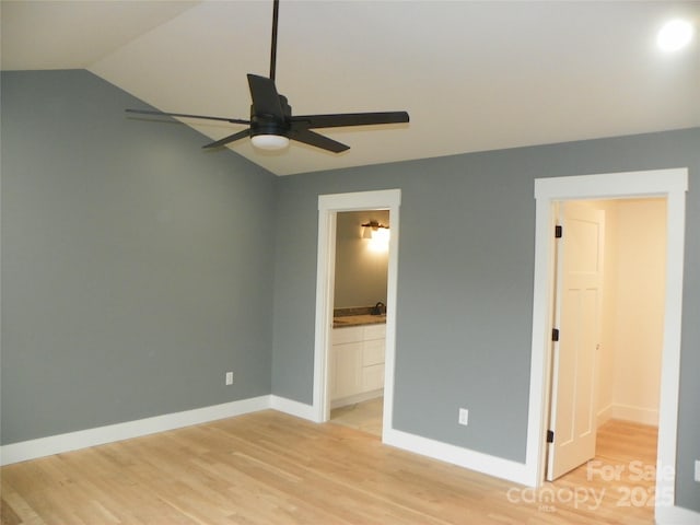 unfurnished bedroom with light wood-style flooring, ensuite bathroom, ceiling fan, vaulted ceiling, and baseboards