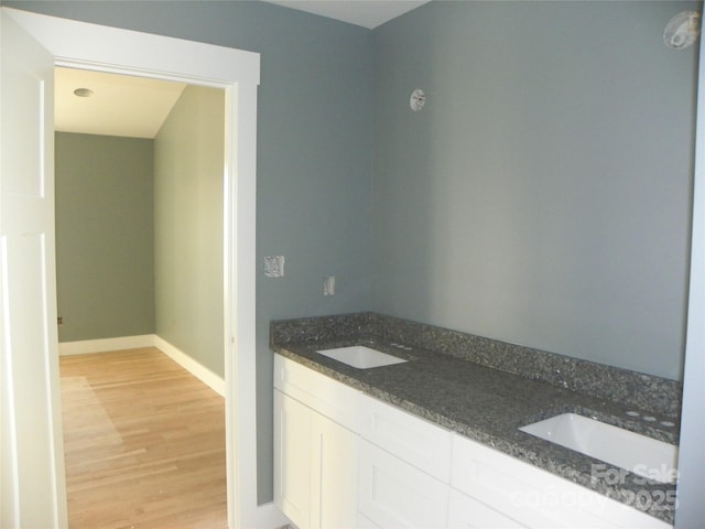 full bath featuring a sink, baseboards, and wood finished floors