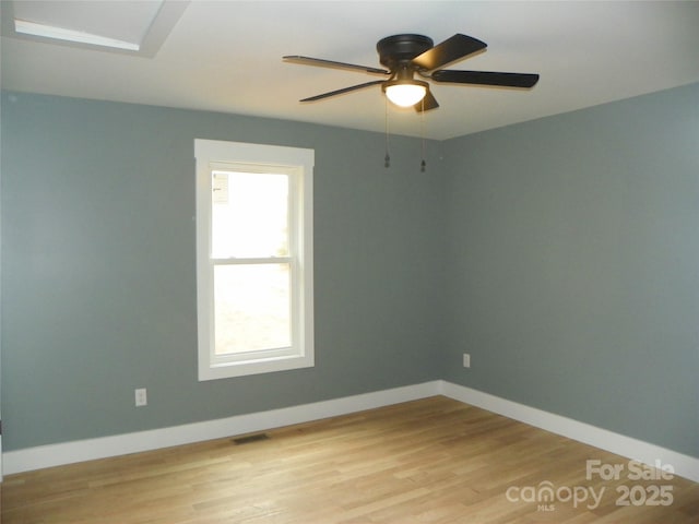 unfurnished room featuring light wood finished floors, a ceiling fan, visible vents, and baseboards