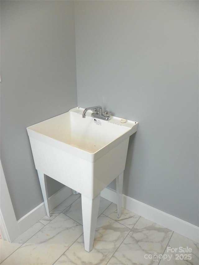 bathroom with marble finish floor, a sink, and baseboards