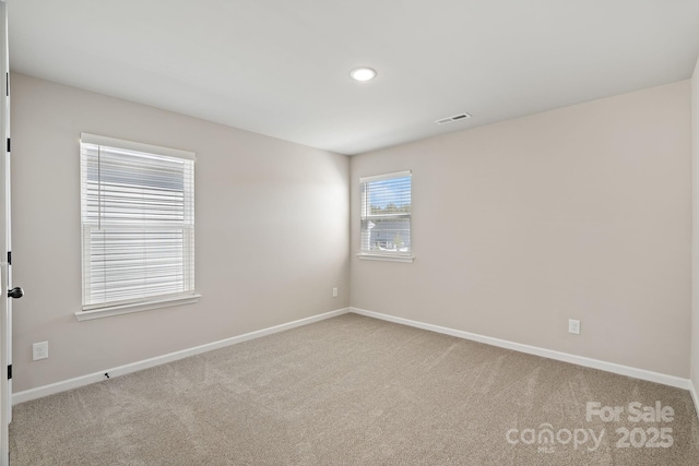 carpeted empty room featuring recessed lighting, visible vents, and baseboards