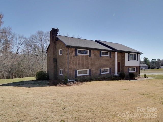 view of front facade featuring brick siding, a chimney, and a front yard