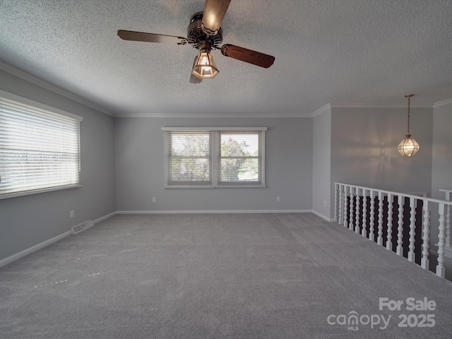 carpeted empty room with a wealth of natural light, visible vents, baseboards, and ornamental molding