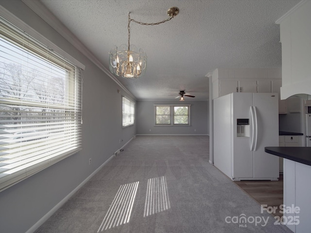 kitchen with light carpet, dark countertops, a textured ceiling, white fridge with ice dispenser, and crown molding