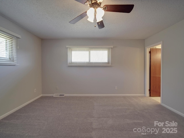 carpeted spare room with a healthy amount of sunlight, visible vents, and baseboards