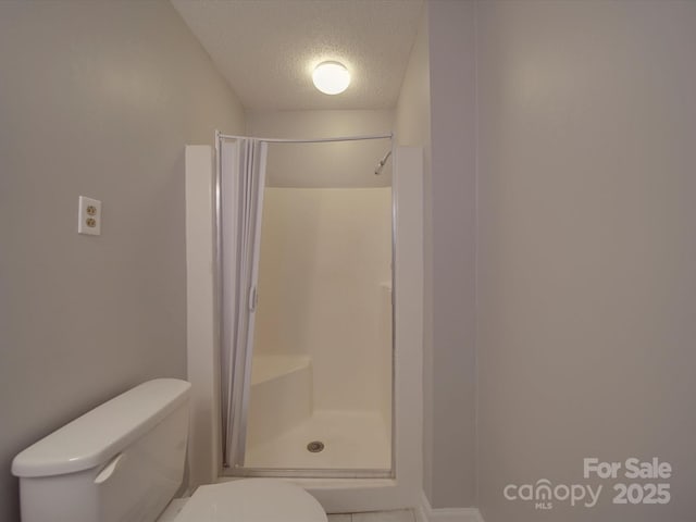 bathroom featuring a shower stall, a textured ceiling, and toilet