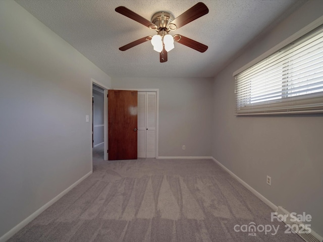 carpeted empty room featuring baseboards, a textured ceiling, and a ceiling fan