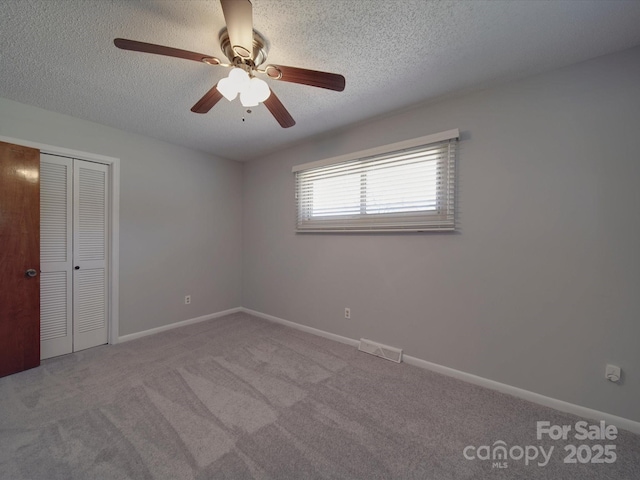 unfurnished room with visible vents, carpet floors, a textured ceiling, and baseboards