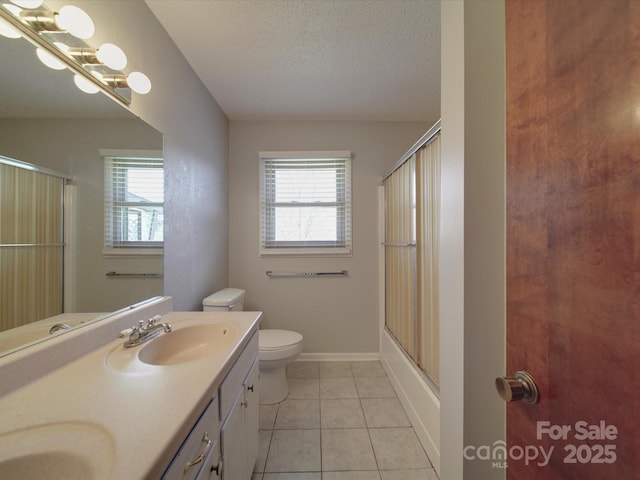 bathroom with a textured ceiling, tile patterned floors, a healthy amount of sunlight, and a sink