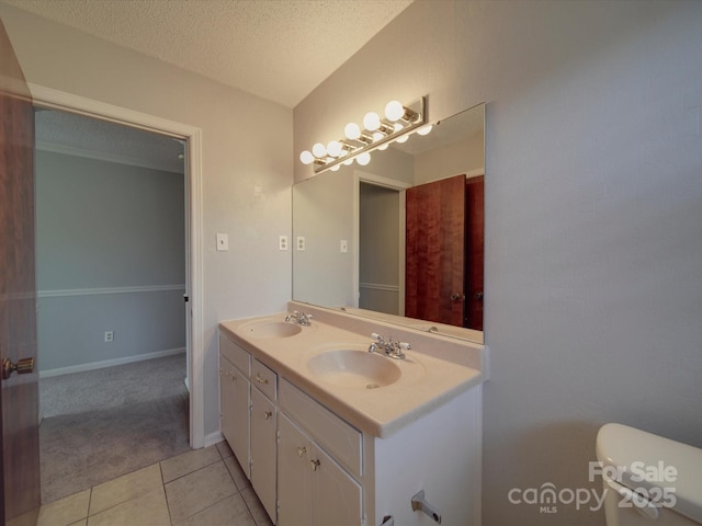 bathroom featuring tile patterned flooring, toilet, a textured ceiling, and a sink