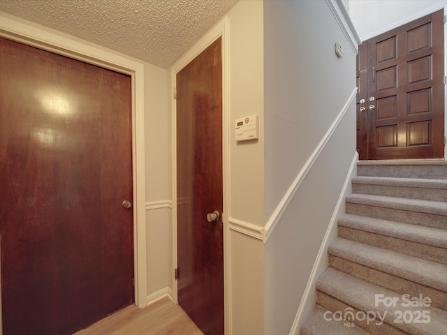 staircase featuring a textured ceiling and wood finished floors