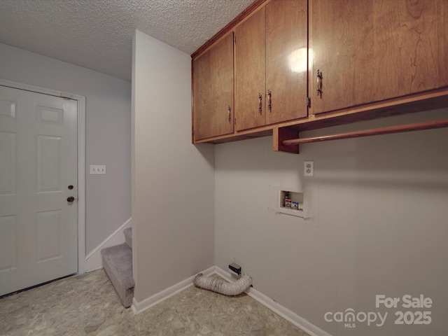 clothes washing area with baseboards, cabinet space, a textured ceiling, and hookup for a washing machine