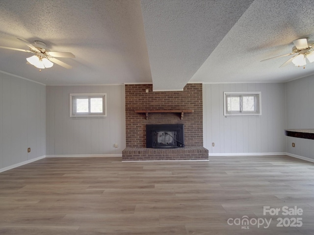 unfurnished living room with a brick fireplace, a healthy amount of sunlight, and wood finished floors