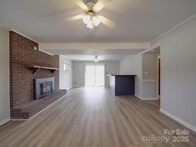 unfurnished living room featuring a ceiling fan, wood finished floors, and a textured ceiling