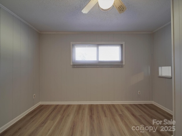 unfurnished room with baseboards, a textured ceiling, wood finished floors, and ornamental molding