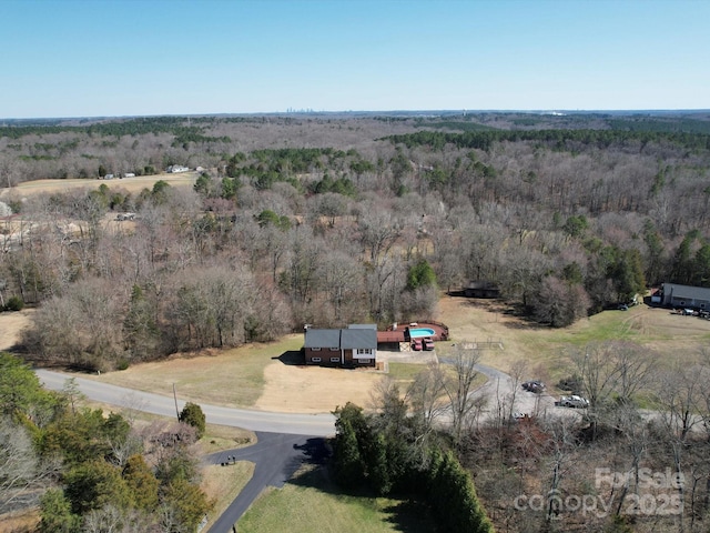 drone / aerial view featuring a view of trees and a rural view