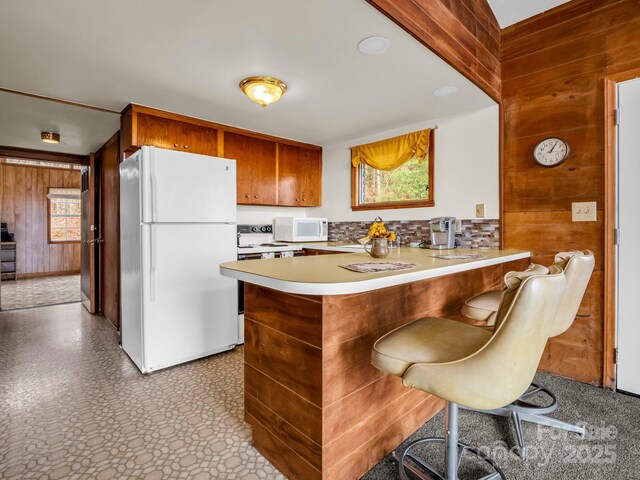 675 Foster Hill Dr, Hendersonville, NC 28739 - kitchen featuring white appliances, wooden walls, a peninsula, light countertops, and brown cabinets