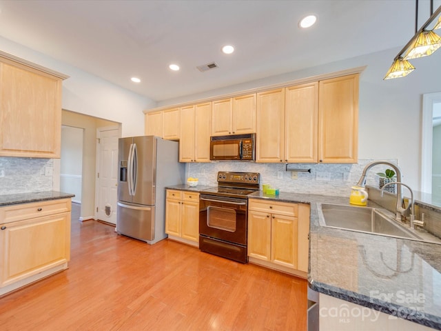 kitchen featuring light brown cabinets, light wood-style flooring, a sink, visible vents, and black appliances