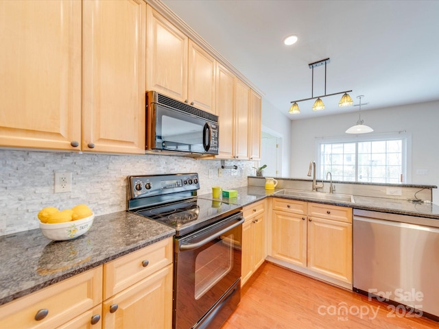 kitchen featuring dark stone counters, black appliances, light brown cabinetry, and a sink