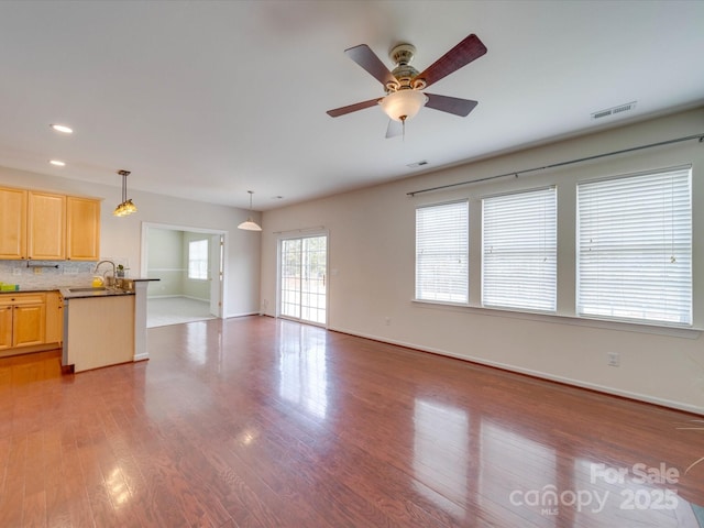 unfurnished living room featuring baseboards, visible vents, and wood finished floors