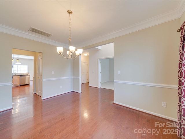 spare room with ornamental molding, wood finished floors, visible vents, and baseboards