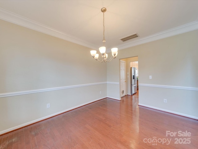 spare room featuring visible vents, crown molding, and wood finished floors