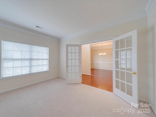 unfurnished room with crown molding, visible vents, a notable chandelier, and french doors