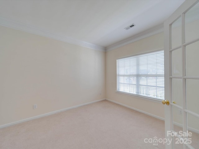 empty room with crown molding, baseboards, visible vents, and light colored carpet