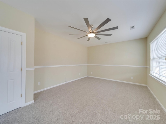 carpeted empty room featuring baseboards, visible vents, and a ceiling fan