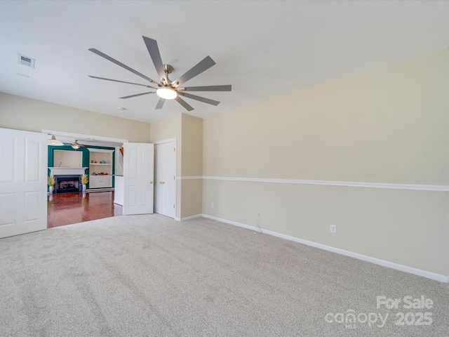 unfurnished bedroom featuring carpet, a fireplace, visible vents, ceiling fan, and baseboards