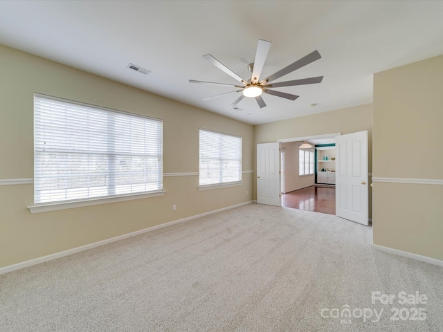 unfurnished room featuring visible vents, carpet, a ceiling fan, and baseboards