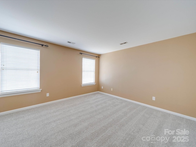 carpeted empty room with visible vents and baseboards