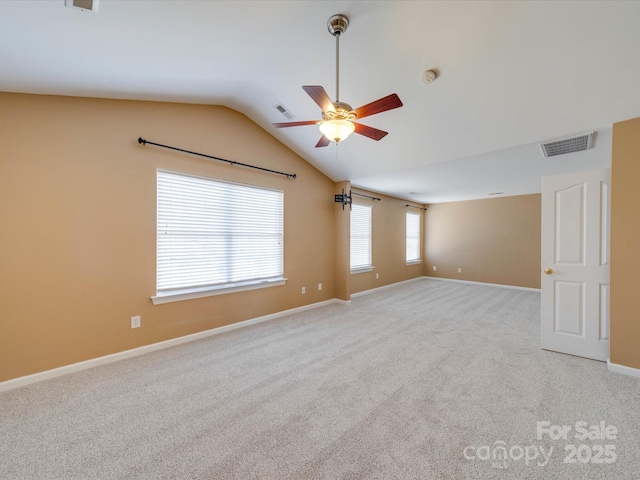 empty room featuring ceiling fan, carpet, visible vents, and vaulted ceiling