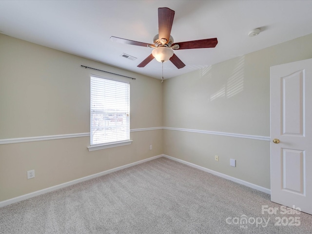 carpeted empty room with ceiling fan, visible vents, and baseboards