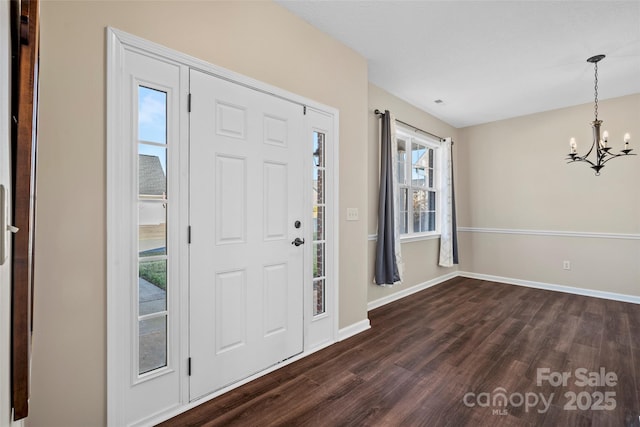 entrance foyer with a chandelier, dark wood-style flooring, and baseboards