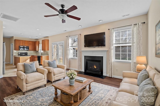 living area with recessed lighting, visible vents, baseboards, and wood finished floors